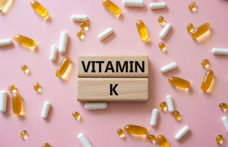Vitamin K symbol. Concept word Vitamin K on wooden blocks. Beautiful pink background with pills. Medicine and Vitamin K concept. Copy spaceの写真素材