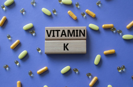 Vitamin K symbol. Concept word Vitamin K on wooden blocks. Beautiful purple background with pills. Medicine and Vitamin K concept. Copy spaceの写真素材