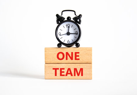 One Team symbol. Concept word One Team on wooden blocks. Beautiful white background with alarm clock. Business and One Team concept. Copy spaceの写真素材