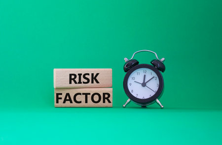 Risk Factor symbol. Wooden blocks with words Risk Factor Beautiful green background with alarm clock. Business and Risk Factor concept. Copy space.の写真素材