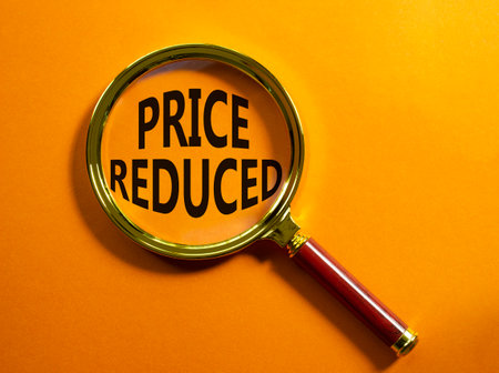 Price reduced symbol. Magnifying Glass with Concept word Price reduced. Beautiful orange background. Business and Price reduced concept. Copy spaceの写真素材