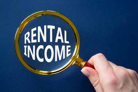 Rental Income symbol. Magnifying glass with words Rental Income. Beautiful deep blue background. Businessman hand. Business and Rental Income concept. Copy space.の写真素材