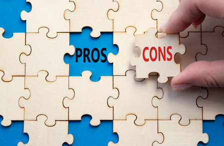 Pros vs Cons symbol. Concept word Pros vs Cons on wooden puzzle. Businessman hand. Beautiful blue background. Business and Pros vs Cons concept. Copy spaceの写真素材