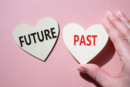 Future or Past symbol. Concept word Future or Past on wooden hearts. Businessman hand. Beautiful pink background. Business and Future or Past concept. Copy spaceの写真素材