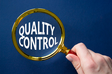 Quality Control symbol. Magnifying glass with words Quality Control. Beautiful deep blue background. Businessman hand. Business and Quality Control concept. Copy space.の写真素材