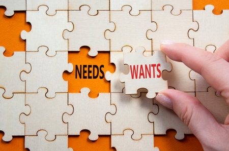 Wants and Needs symbol. Concept word Wants and Needs on wooden blocks. Businessman hand. Beautiful orange background. Business and Wants and Needs concept. Copy spaceの写真素材
