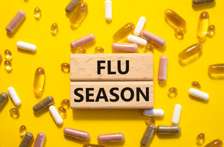 Flu Season symbol. Concept word Flu Season on wooden blocks. Beautiful yellow background with pills. Medicine and Flu Season concept. Copy spaceの写真素材
