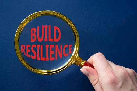 Build resilience symbol. Magnifying glass with words Build resilience. Beautiful deep blue background. Businessman hand. Business and Build resilience concept. Copy space.の写真素材
