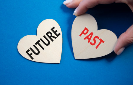 Future or Past symbol. Concept word Future or Past on wooden hearts. Businessman hand. Beautiful blue background. Business and Future or Past concept. Copy spaceの写真素材