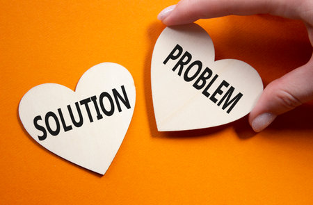 Solution vs Problem symbol. Concept word Solution vs Problem on wooden hearts. Businessman hand. Beautiful orange background. Business and Solution vs Problem concept. Copy spaceの写真素材