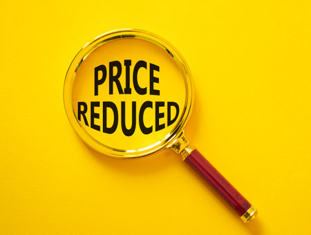 Price reduced symbol. Magnifying Glass with Concept word Price reduced. Beautiful yellow background. Business and Price reduced concept. Copy spaceの写真素材