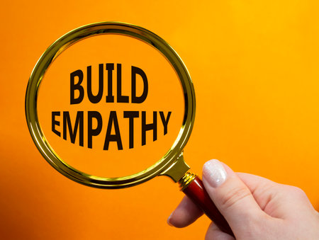 Build empathy symbol. Magnifying glass with words Build empathy. Beautiful orange background. Businessman hand. Business and Build empathy concept. Copy space.の写真素材