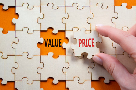 Price and Value symbol. Concept word Price and Value on wooden puzzle. Businessman hand. Beautiful orange background. Business and Price and Value concept. Copy spaceの写真素材
