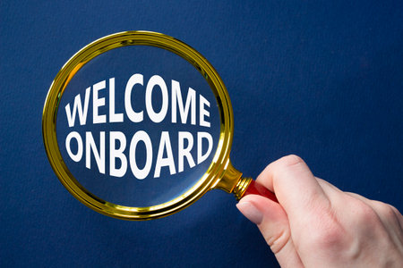 Welcome onboard symbol. Magnifying Glass with Concept word Welcome onboard. Businessman hand. Beautiful deep blue background. Business and Welcome onboard concept. Copy spaceの写真素材