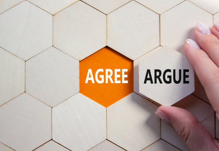 Agree or Argue symbol. Concept word Agree or Argue on wooden comb puzzle. Businessman hand. Beautiful orange background. Business and Agree or Argue concept. Copy spaceの写真素材