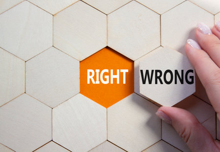 Right or Wrong symbol. Concept word Right or Wrong on wooden comb puzzle. Businessman hand. Beautiful orange background. Business and Right or Wrong concept. Copy spaceの写真素材