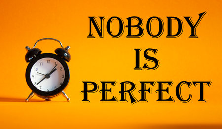 Nobody is Perfect symbol. Concept word Nobody is Perfect on Beautiful orange background with alarm clock. Business and Nobody is Perfect concept. Copy spaceの写真素材