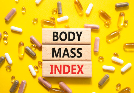 Body Mass Index symbol. Concept word Body Mass Index on wooden blocks. Beautiful yellow background with pills. Medicine and Body Mass Index concept. Copy spaceの写真素材