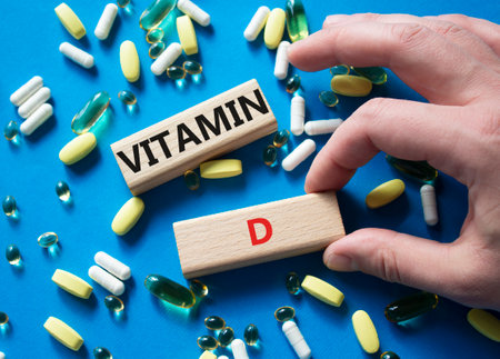 Vitamin D symbol. Concept word Vitamin D on wooden blocks. Beautiful blue background with pills. Doctor hand. Medicine and Vitamin D concept. Copy spaceの写真素材