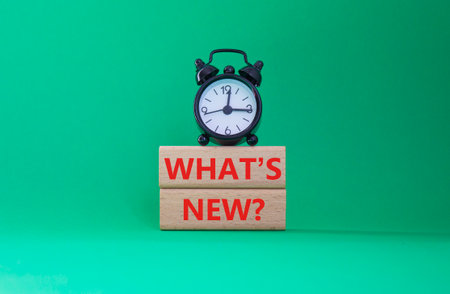 What is new symbol. Concept word What is new on wooden blocks. Beautiful green background with alarm clock. Business and What is new concept. Copy spaceの写真素材