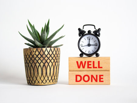 Well done symbol. Wooden blocks with words Well done. Beautiful white background with alarm clock and succulent plant. Business and Well done concept. Copy space.の写真素材