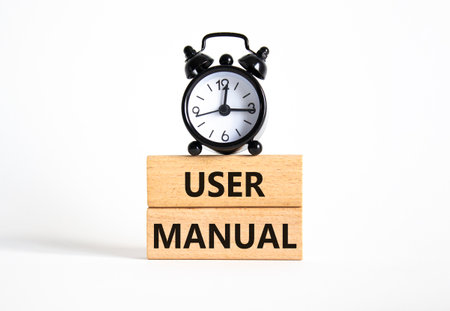 User Manual symbol. Concept words User Manual on wooden blocks. Beautiful white background with alarm clock. Business and User Manual concept. Copy space.の写真素材