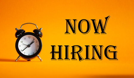 Now Hiring symbol. Concept word Now Hiring on Beautiful orange background with alarm clock. Business and Now Hiring concept. Copy spaceの写真素材