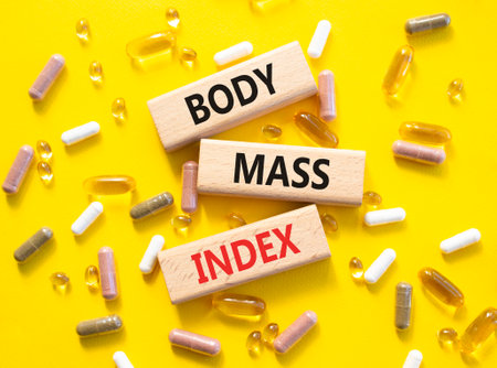 Body Mass Index symbol. Concept word Body Mass Index on wooden blocks. Beautiful yellow background with pills. Medicine and Body Mass Index concept. Copy spaceの写真素材