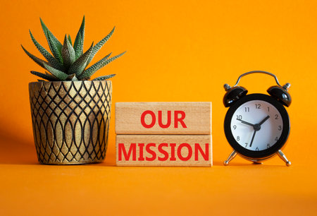 Our Mission symbol. Wooden blocks with words Our Mission. Beautiful orange background with alarm clock and succulent plant. Business and Our Mission concept. Copy space.の写真素材