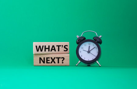 What is next symbol. Concept words What is next on wooden blocks. Beautiful green background with alarm clock. Business and What is next concept. Copy space.の写真素材