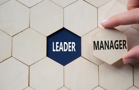 Leader or Manager symbol. Concept word Leader or Manager on wooden comb puzzle. Businessman hand. Beautiful deep blue background. Business and Leader or Manager concept. Copy spaceの写真素材