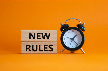 New rules symbol. Concept word New rules on wooden blocks. Beautiful orange background with alarm clock. Business and New rules concept. Copy spaceの写真素材