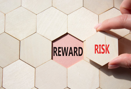 Risk or Reward symbol. Concept word Risk or Reward on wooden comb puzzle. Businessman hand. Beautiful pink background. Business and Risk or Reward concept. Copy spaceの写真素材