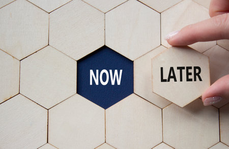Now vs Later symbol. Concept word Now vs Later on wooden comb puzzle. Businessman hand. Beautiful deep blue background. Business and Now vs Later concept. Copy spaceの写真素材