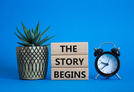 Concept words The Story Begins on wooden blocks. Beautiful blue background with alarm clock and...