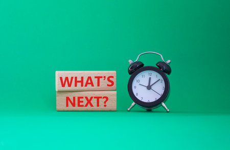 What is next symbol. Concept words What is next on wooden blocks. Beautiful green background with alarm clock. Business and What is next concept. Copy space.の写真素材