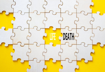 Life or Death symbol. Concept word Life or Death on wooden puzzle. Beautiful yellow background. Business and Life or Death concept. Copy spaceの写真素材