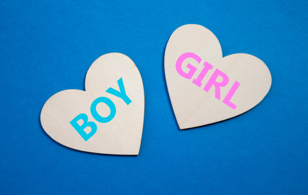 Boy or Girl symbol. Concept word Boy or Girl on wooden hearts. Beautiful blue background. Gender and Boy or Girl concept. Copy spaceの写真素材