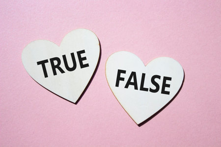 True or False symbol. Concept word True or False on wooden hearts. Beautiful pink background. Business and True or False concept. Copy spaceの写真素材