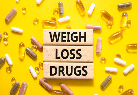 Medicine symbol. Concept words Weight Loss Drugs on wooden blocks. Beautiful yellow background with pills. Medicine concept and Weight Loss Drugs. Copy spaceの写真素材