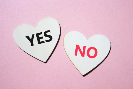 Yes or No symbol. Concept word Yes or No on wooden hearts. Beautiful pink background. Business and Yes or No concept. Copy spaceの写真素材