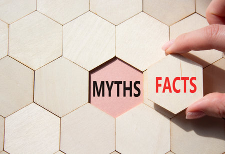 Facts or Myths symbol. Concept word Facts or Myths on wooden comb puzzle. Businessman hand. Beautiful pink background. Business and Facts or Myths concept. Copy spaceの写真素材