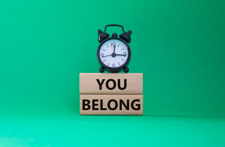 You belong symbol. Concept words You belong on wooden blocks. Beautiful green background with alarm clock. Business and You belong concept. Copy space.の写真素材