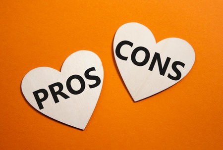 Pros vs Cons symbol. Concept word Pros vs Cons on wooden hearts. Beautiful orange background. Business and Pros vs Cons concept. Copy spaceの写真素材