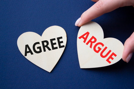 Agree or Argue symbol. Concept word Agree or Argue on wooden hearts. Businessman hand. Beautiful deep blue background. Business and Agree or Argue concept. Copy spaceの写真素材