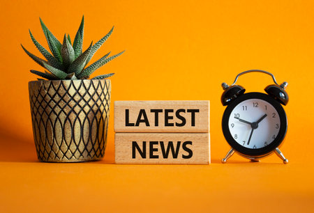 Latest News symbol. Concept words Latest News on wooden blocks. Beautiful orange background with alarm clock and succulent plant. Business and Latest News concept. Copy space.の写真素材