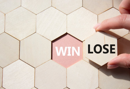 Win or Lose symbol. Concept word Win or Lose on wooden comb puzzle. Businessman hand. Beautiful pink background. Business and Win or Lose concept. Copy spaceの写真素材