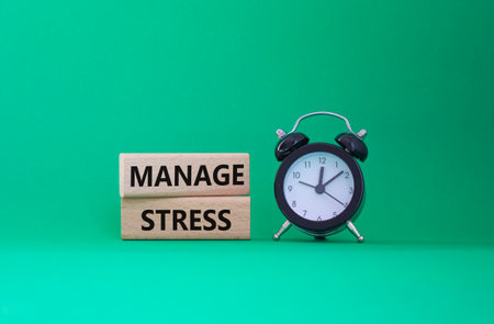 Manage stress symbol. Concept word Manage stress on wooden blocks. Beautiful green background with alarm clock. Business and Management stress concept. Copy spaceの写真素材