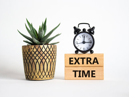 Extra time symbol. Concept word Extra time on wooden blocks. Beautiful white background with alarm clock and succulent plant. Business and Extra time concept. Copy spaceの写真素材