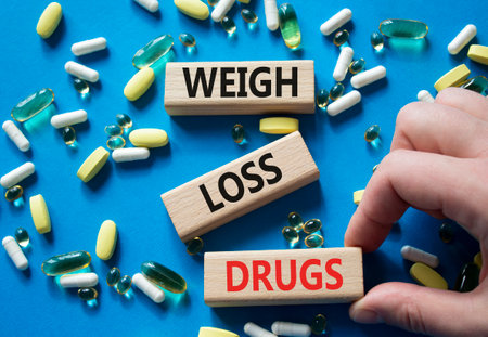 Medicine symbol. Concept words Weight Loss Drugs on wooden blocks. Doctor Hand. Beautiful blue background with pills. Medicine concept and Weight Loss Drugs. Copy spaceの写真素材